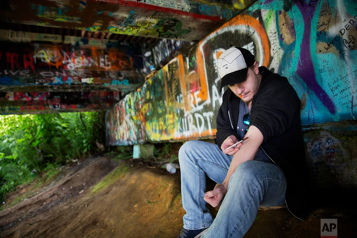 Forrest Wood, 24, injects heroin into this arm under a bridge along the Wishkah River at Kurt Cobain Memorial Park in Aberdeen, Wash., Tuesday, June 13, 2017. Wood grew up here, watching drugs take hold of his relatives, and he swore to himself that he would get out of this place, maybe spend his days in the woods as a park ranger. But he started taking opioid painkillers as a teenager, and before he knew it he was shooting heroin, a familiar first chapter in the story of American addiction. (AP Photo/David Goldman)