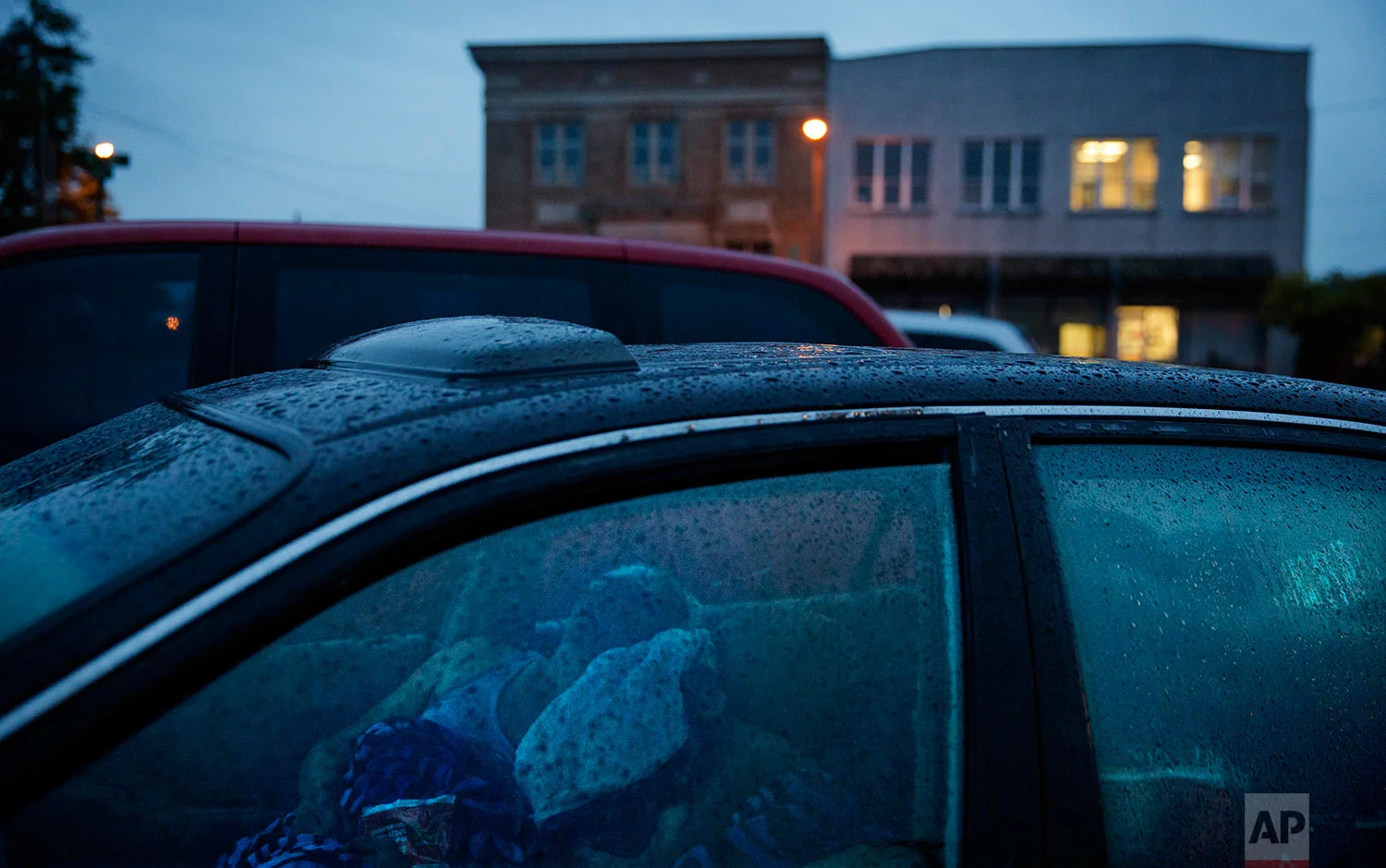 Staci Hadley, left, and boyfriend Deric Hensler, hidden, sleep in their car overnight in a parking lot outside the methadone clinic before it opens where they get treated for their drug addiction in Hoquiam, Wash., Thursday June 15, 2017. "Not too long ago we were thinking 'oh how the mighty have fallen'," said Hadley. The two used to have jobs, bank accounts, credit cards, a house before Hensler lost his job and insurance to cover methadone treatments. "I know we're kind of messed out right now," added Hadley. "But this is not my life." (AP Photo/David Goldman)