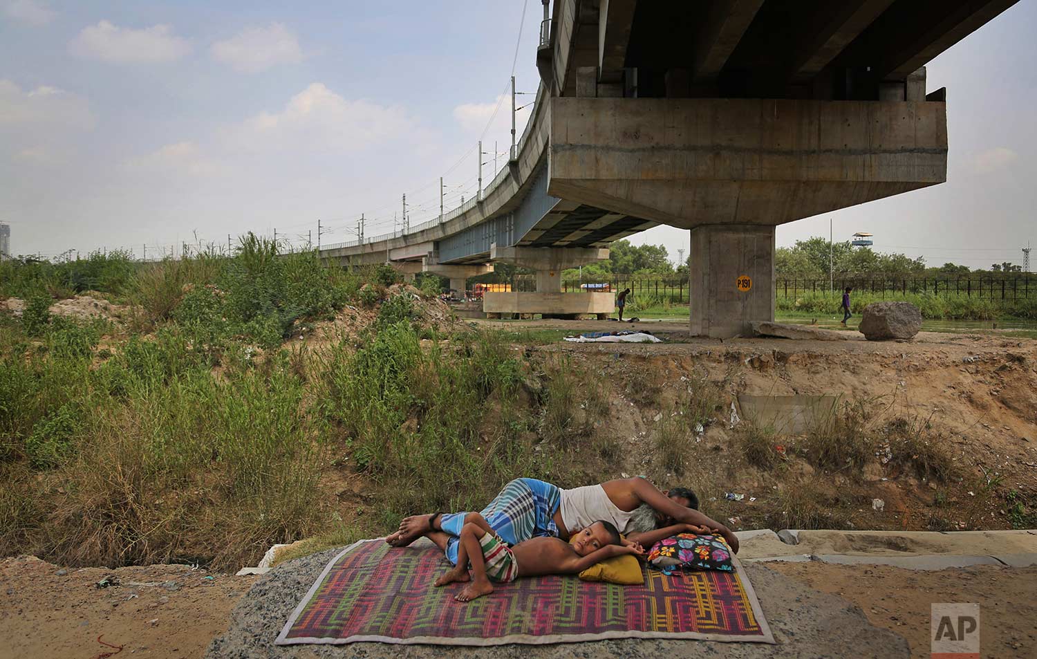  A Rohingya refugee takes a nap as a child lies next to him outside a temporary shelter in New Delhi, India, Wednesday, Aug. 16, 2017. (AP Photo/Altaf Qadri) 