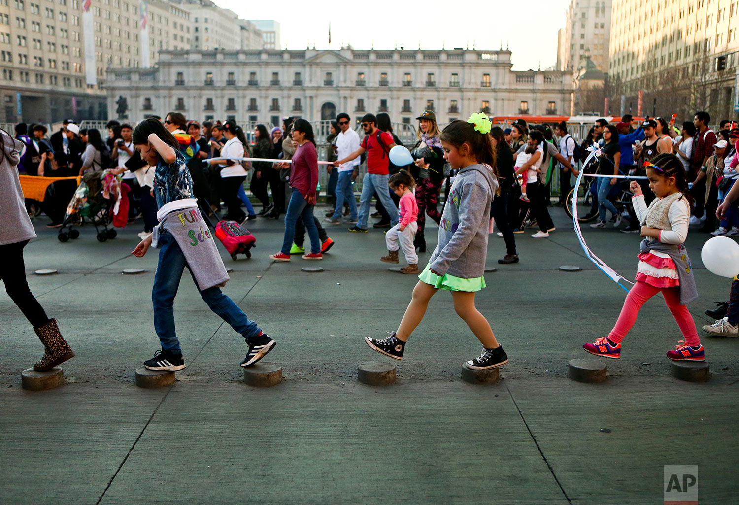  In this July 1, 2017 photo, transgender girls Selenna, center right, and Mathilda, far right, walk on street stumps with other children outside La Moneda government palace during a Gay Pride march in Santiago, Chile. The government is backing a bill