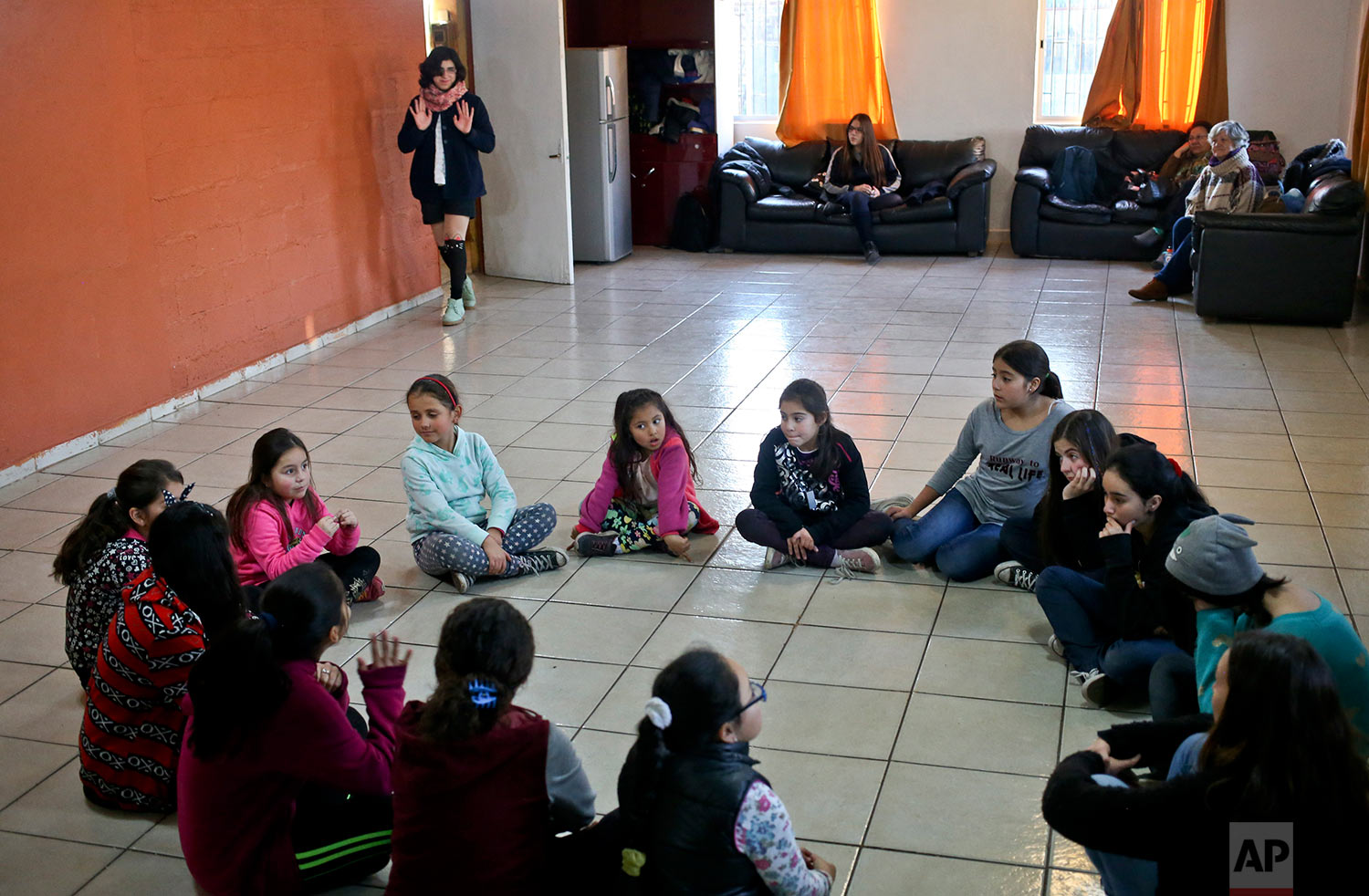  In this June 30, 2017 photo, transgender girls Angela, arriving, top, and Selenna, sitting in the circle at top left and wearing a blue sweatshirt, take a theater and dance class with girls at their community center Santiago, Chile. Angela, 13, who 