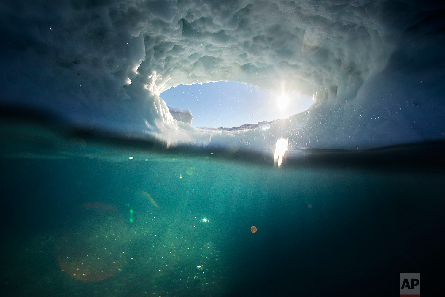  The submerged section of an iceberg is illuminated underwater by the setting sun through a hole melted in the iceberg floating in the Nuup Kangerlua Fjord near Nuuk in southwestern Greenland, Tuesday, Aug. 1, 2017. (AP Photo/David Goldman) 