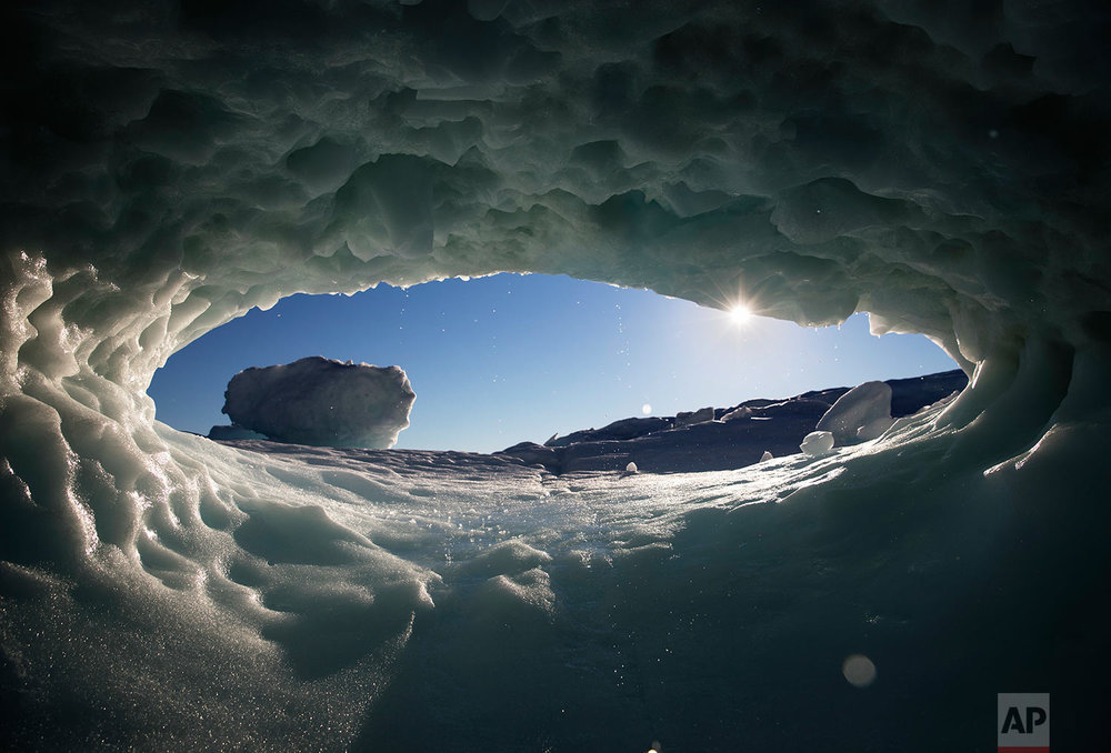  The sun sets through a hole melted in an iceberg floating in the Nuup Kangerlua Fjord near Nuuk in southwestern Greenland, Tuesday, Aug. 1, 2017. (AP Photo/David Goldman) 