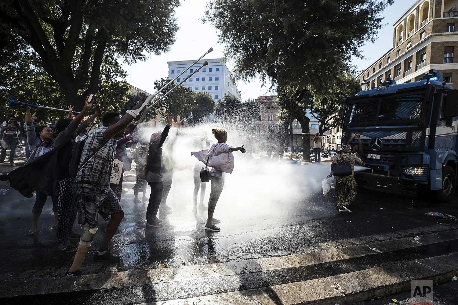 Law enforcement officers use water cannons to disperse migrants in downtown Rome, Thursday, Aug. 24, 2017. Protests erupted as police continued an operation to evict some 800 Eritrean and Ethiopian refugees from a building they have occupied since 2013, despite protests from the U.N. refugee agency, UNICEF, and humanitarian organizations. (Angelo Carconi/ANSA via AP)