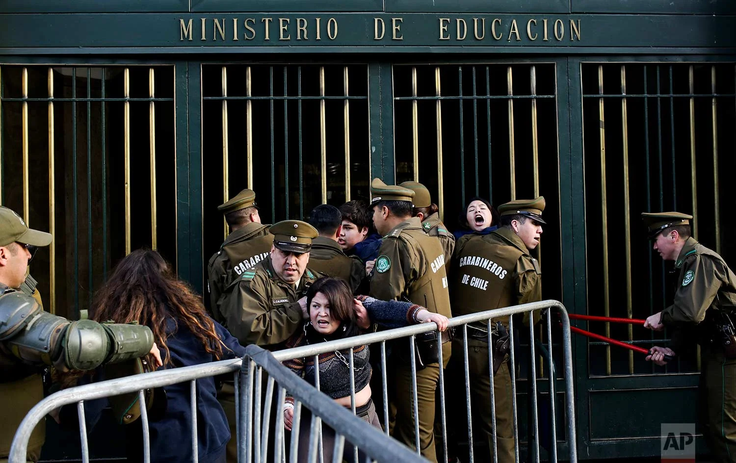 National Police remove protesting high school students who chained themselves to the Ministry of Education building in Santiago, Chile, Wednesday, Aug. 23, 2017. The students are demanding education reform, including free access to school for all ages. (AP Photo/Esteban Felix)