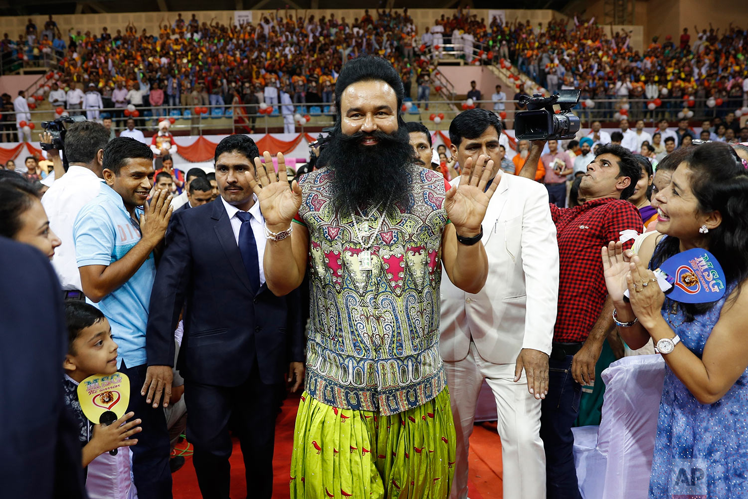  In this Oct. 5, 2016 photo, Indian spiritual guru who calls himself Dr. Saint Gurmeet Singh Ram Rahim Insan, center, greets followers as he arrives for a press conference ahead of the release of his new movie "MSG, The Warrior Lion Heart," in New De