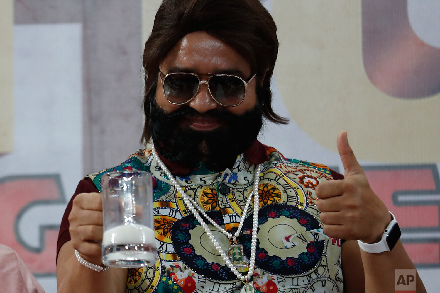  In this May 17, 2017 photo, Indian spiritual leader turned actor who calls himself Dr. Saint Gurmeet Singh Ram Rahim Insan gestures as he holds up a glass of milk at a "Cow Milk Party" during the premiere of the movie "Jattu Engineer" in New Delhi, 