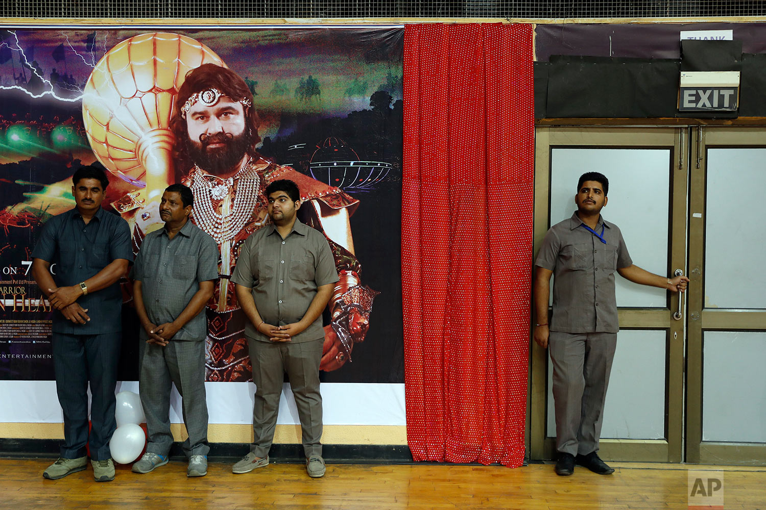  In this Oct. 5, 2016, file photo, security officers stand watch by a poster of Indian spiritual guru, who calls himself Dr. Saint Gurmeet Singh Ram Rahim Insan, during a press conference ahead of the release of the guru's film "MSG, The Warrior Lion