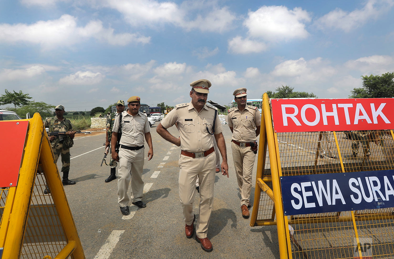  Indian policemen stand guard at a temporary road blockade near Sunaria Jail where Dera Sacha Sauda sect chief Gurmeet Ram Rahim Singh is being held in Rohtak, about 80 kilometers (50 miles) from New Delhi, India, Monday, August 28, 2017. A curfew is