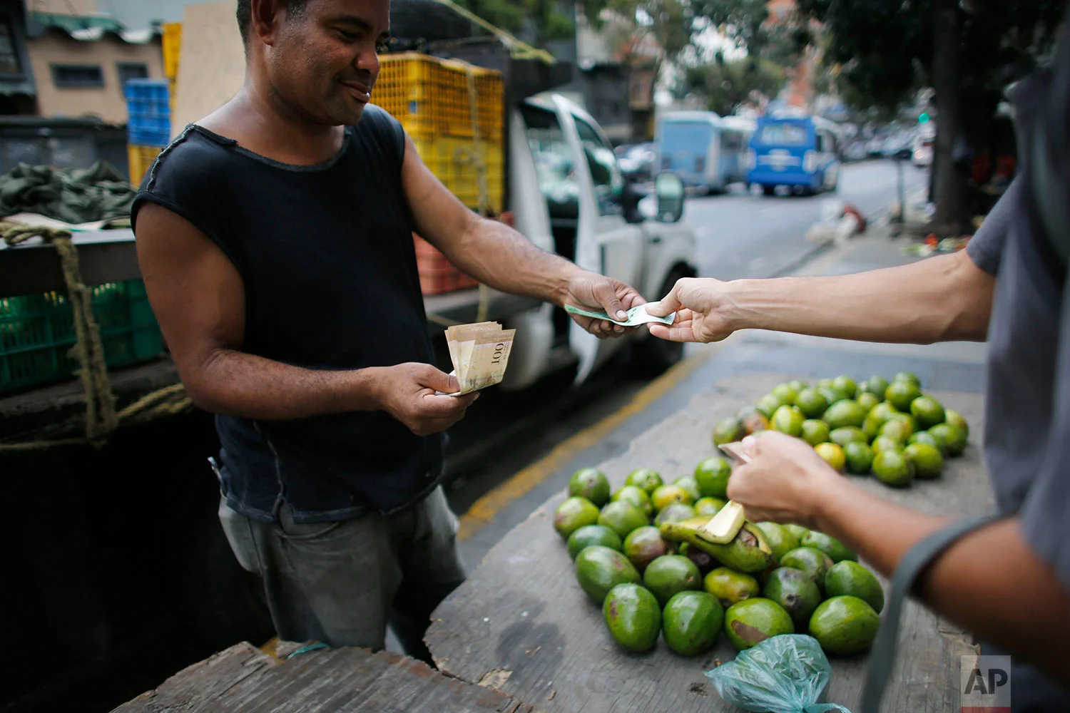 A street vendor sells avocados, Aug. 23, 2017, Caracas, Venezuela. Venezuelan President Nicolas Maduro has been celebrating calm returning to the streets after months of deadly protests, yet the country’s imploding economy poses an ever more severe threat. (AP Photo/Ariana Cubillos)
