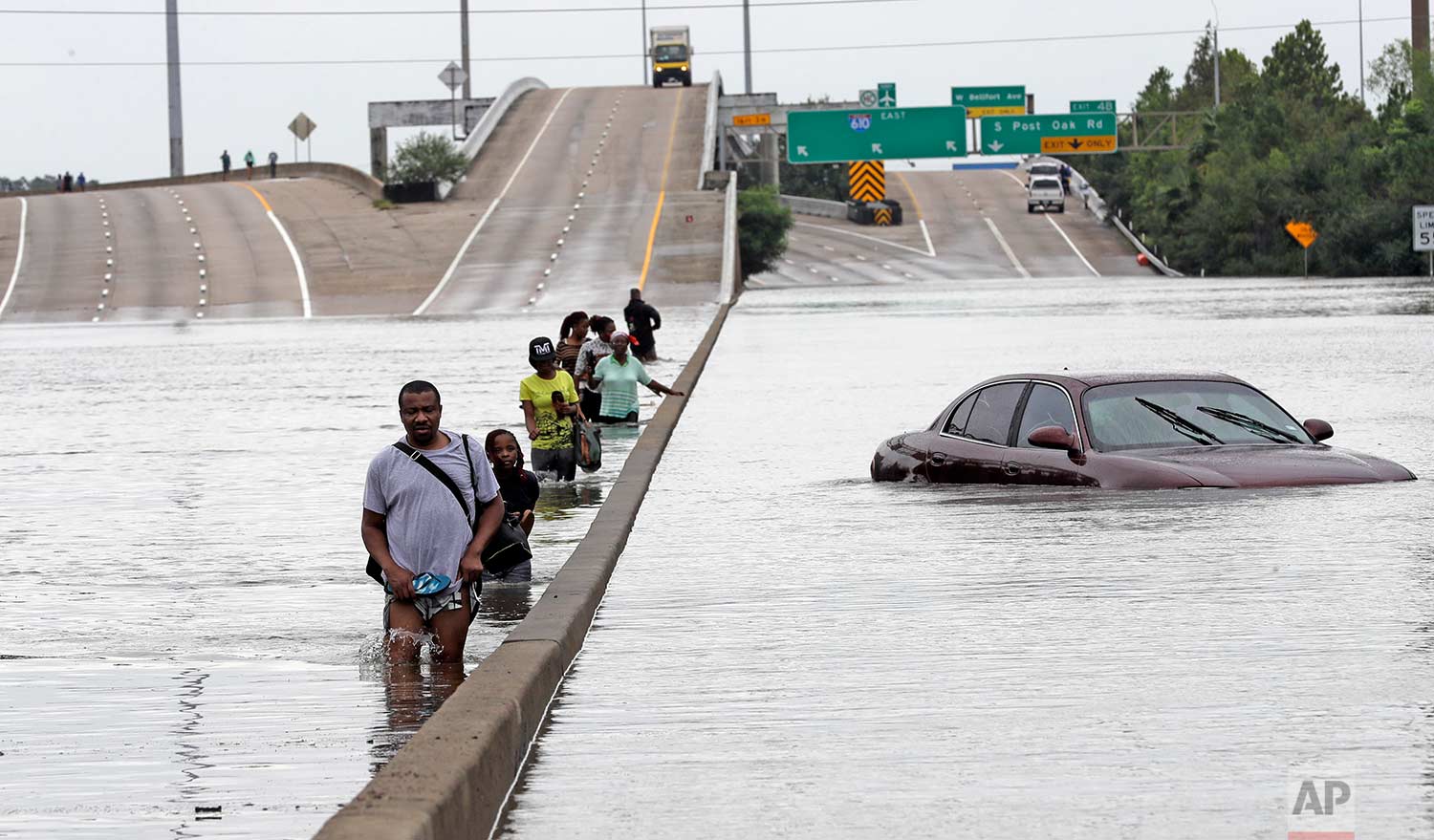 Evacuees wade down a flooded section of Interstate 610 as floodwaters from Tropical Storm Harvey rise Sunday, Aug. 27, 2017, in Houston. (AP Photo/David J. Phillip)