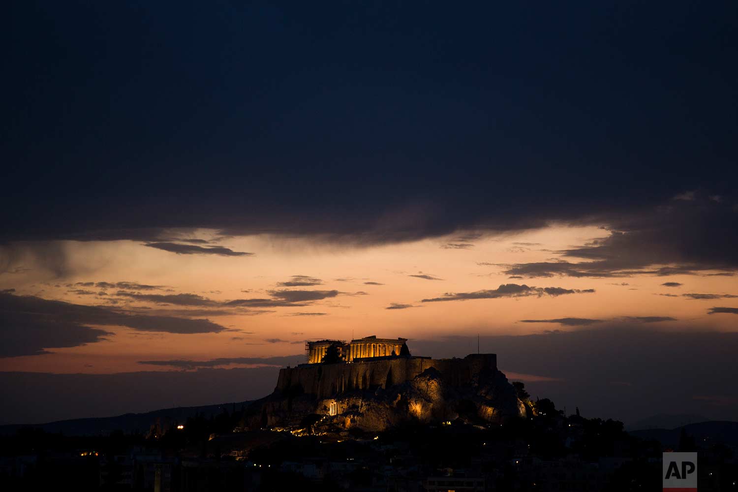 Clouds cover the Athenian sky as the ancient Acropolis hill and the ruins of the fifth century B.C. Parthenon temple are illuminated on Tuesday, Aug. 29, 2017. (AP Photo/Petros Giannakouris)