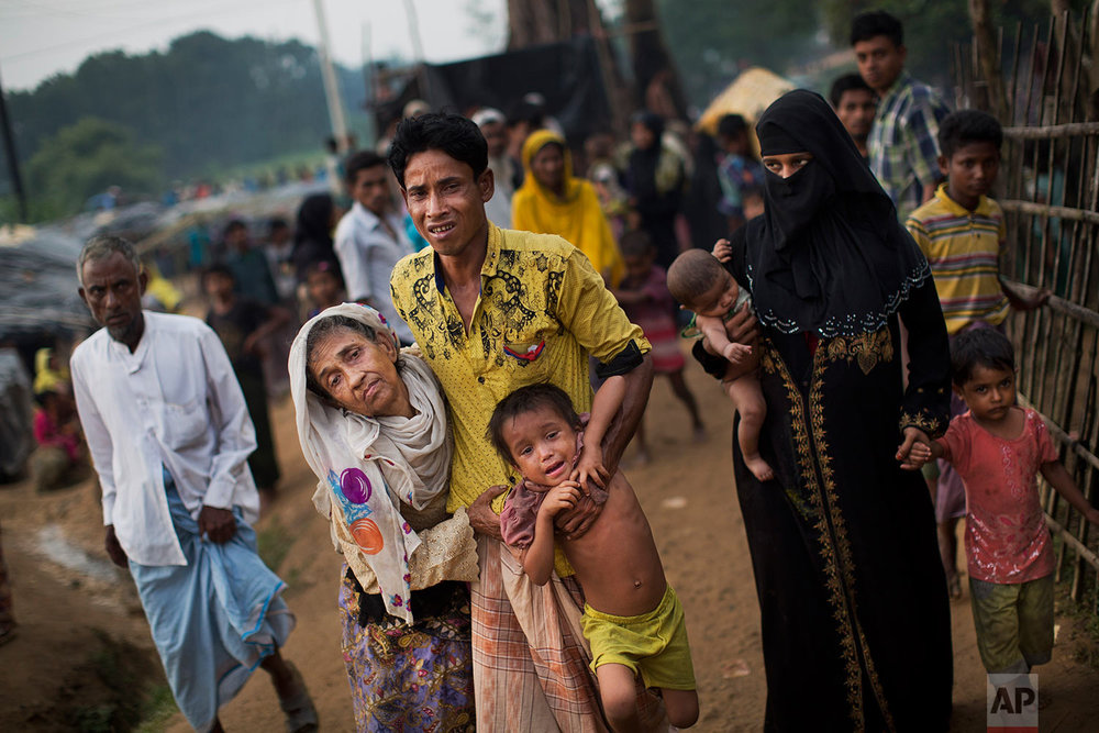  An exhausted Rohingya helps an elderly family member and a child as they arrive at Kutupalong refugee camp after crossing from Myanmmar to the Bangladesh side of the border, in Ukhia, Tuesday, Sept. 5, 2017. The man said he lost several family membe