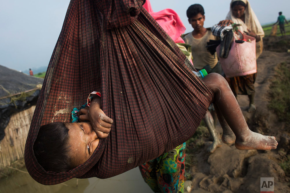 A Rohingya child is carried on a sling while his family walk through rice fields after crossing the border into Bangladesh near Cox's Bazar's Teknaf area, Tuesday, Sept. 5, 2017. (AP Photo/Bernat Armangue) 