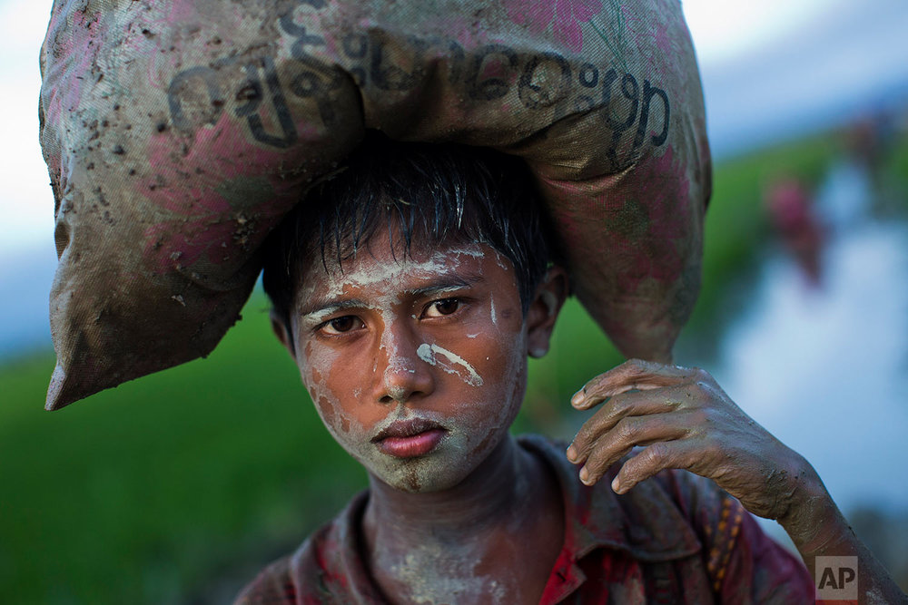  A Rohingya boy, an ethnic minority from Myanmar, carries a sack of belongings on his head and walks through rice fields after crossing over to the Bangladesh side of the border near Cox's Bazar's Teknaf area, Friday, Sept. 1, 2017. Myanmar's militar