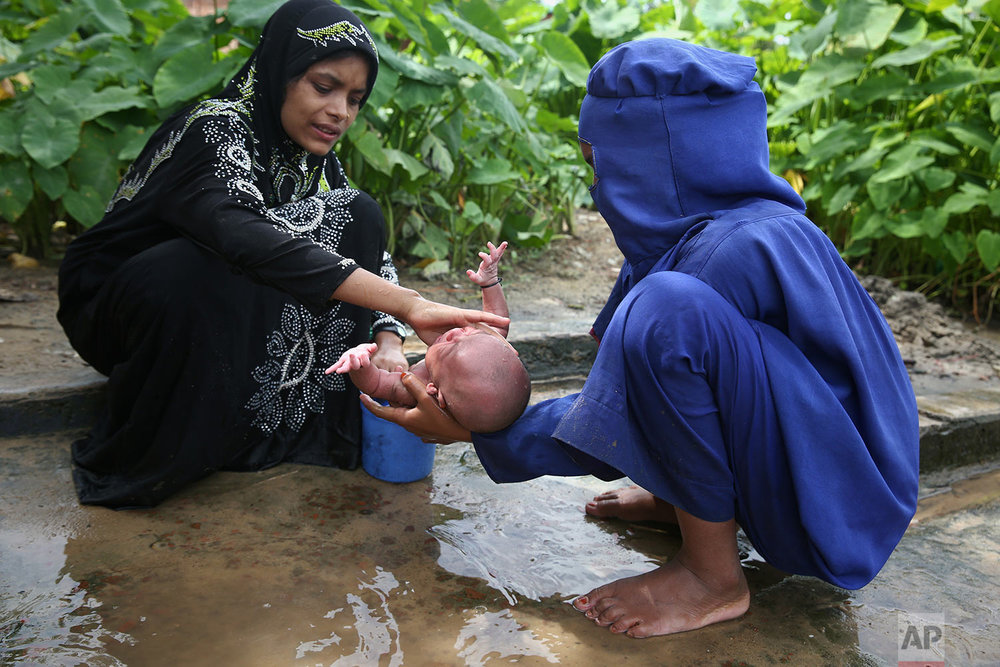  Myanmar's Rohingya Muslim ethnic minority women bathe a week-old infant at the Kutupalong makeshift refugee camp in Cox's Bazar, Bangladesh, Wednesday, Aug. 30, 2017. Thousands of Rohingya Muslims have fled fresh violence in Myanmar and crossed into