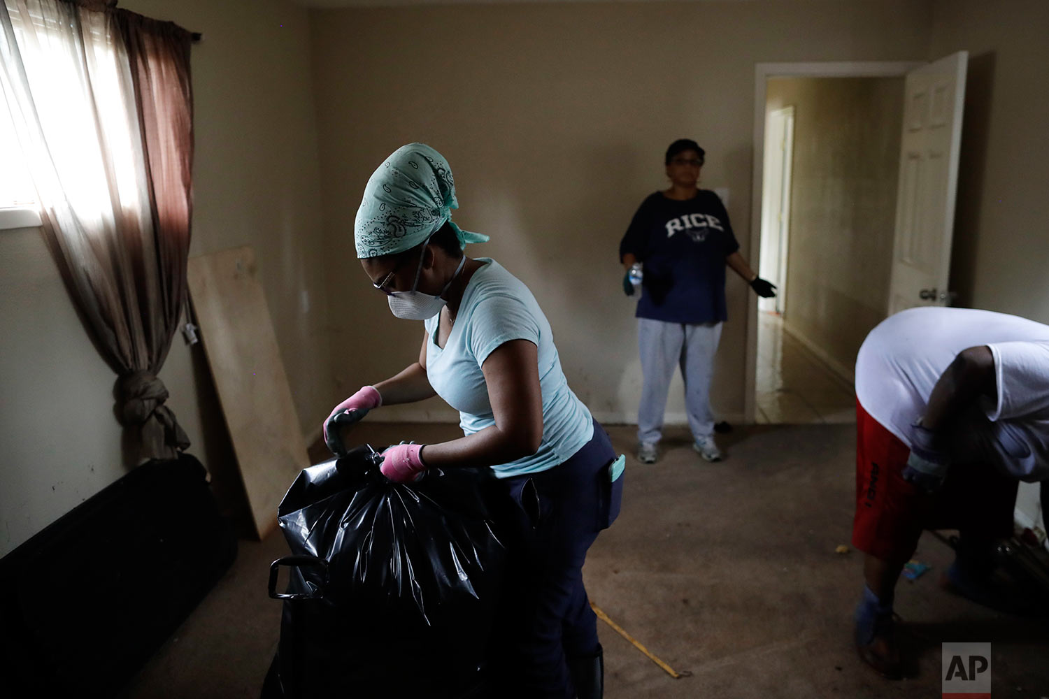  In this Sunday, Sept. 3, 2017, photo, Erica Gradney, left, bags up items in front of Martha Tolfree, center, as they clean up damage to a friend's flooded home in Houston.  (AP Photo/Gregory Bull) 