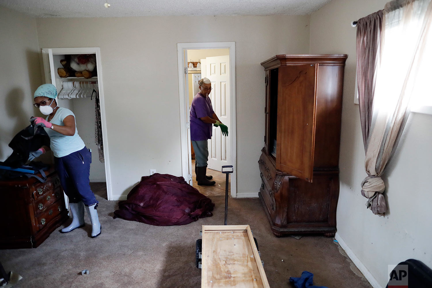  In this Sunday, Sept. 3, 2017, photo, Pauline Simpson, center, gets help from Erica Gradney, left, as they clean up damage to Simpson's flooded home in Houston. (AP Photo/Gregory Bull) 