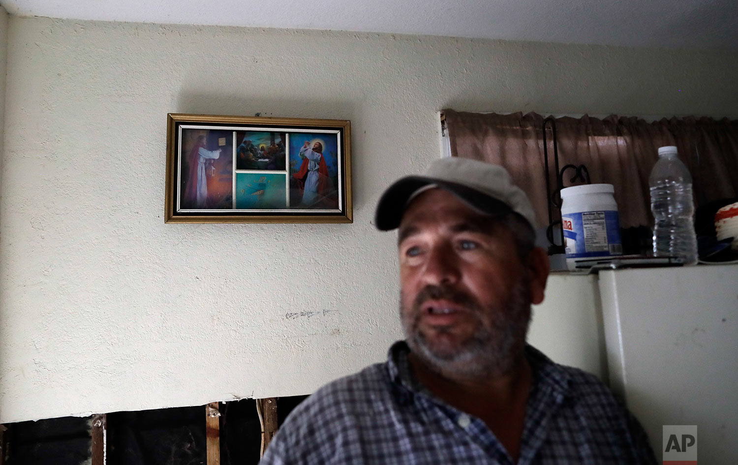  In this Sunday, Sept. 3, 2017, photo, religious images are almost all that still hang on the walls of Lino Saldana's home, as he talks about the floodwaters from a nearby bayou that swept through his home in Houston. Like many of his neighbors on fl