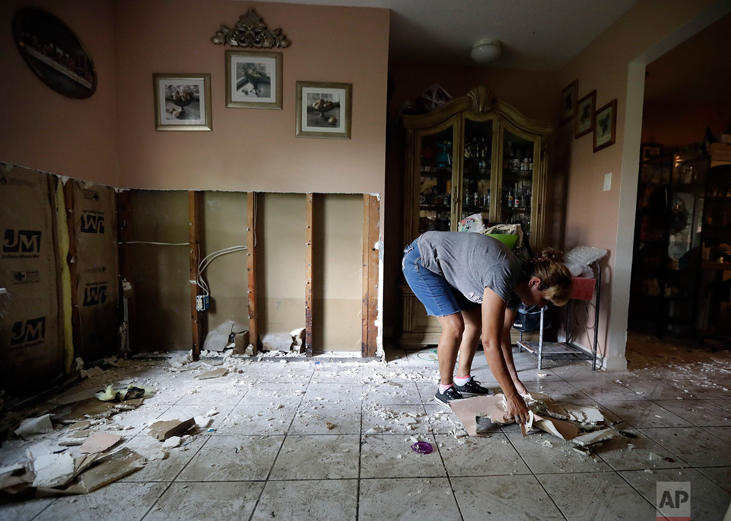  In this Sunday, Sept. 3, 2017, photo, Ana Benavidez picks up damaged drywall as she cleans out her flooded home in Houston. (AP Photo/Gregory Bull) 