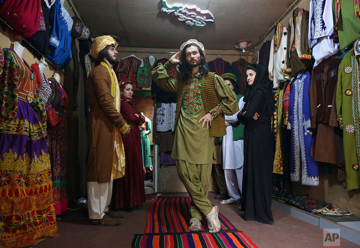  Omid Arman, center, a model for traditional embroidered Afghan clothing, practices modeling, in Kabul, Afghanistan on Aug. 3, 2017. His employer, Ajmal Haqiqi, who hails from the restive Ghazni province, said he exhibits and markets the traditional 
