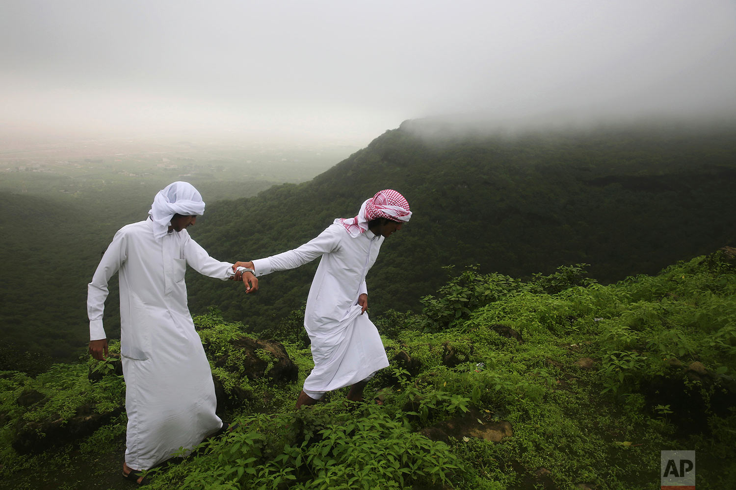  Mohammad al-Bariki, right, 17, leads his half-brother Sagheer al-Bariki, 17, across a cliff ledge in the Jabal Ayoub mountains north of Salalah, Oman on Aug. 2, 2017. (AP Photo/Sam McNeil) 