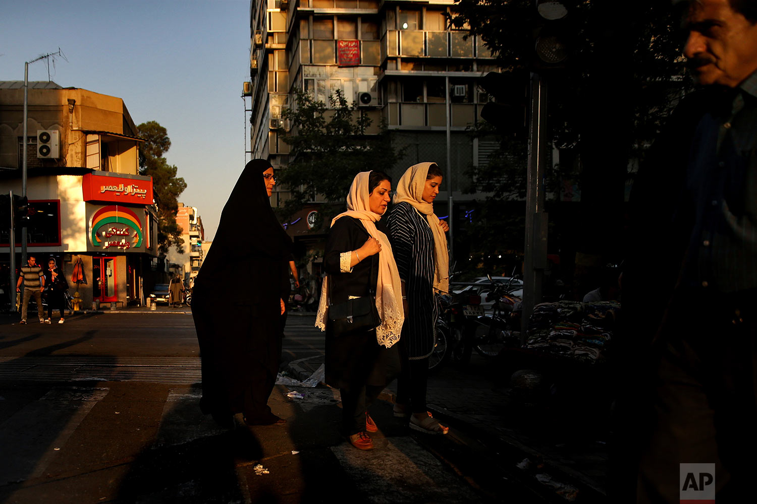  Iranian women cross a street while one of them wears the "chador" in downtown Tehran, Iran on Aug. 24, 2017. (AP Photo/Vahid Salemi) 