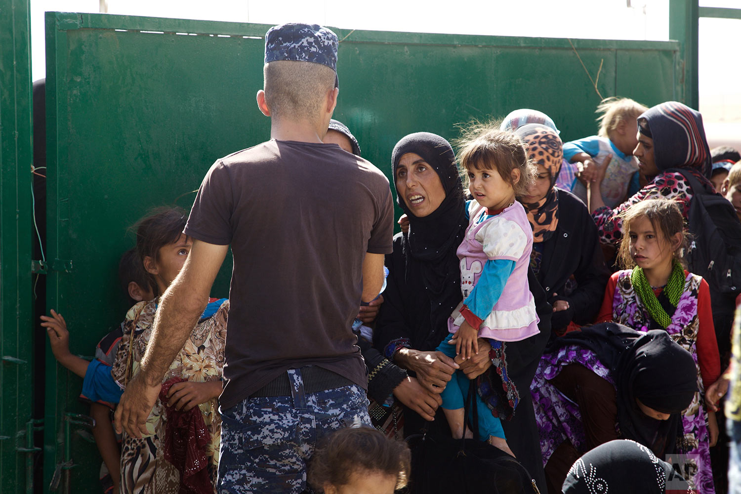  An Iraqi policeman gestures at a group of displaced women and children at a collection point west of Mosul on the outskirts of Tal Afar, Iraq, Saturday, Aug. 26, 2017. The Iraqi military said on Saturday that they had taken 90 percent of the town, o
