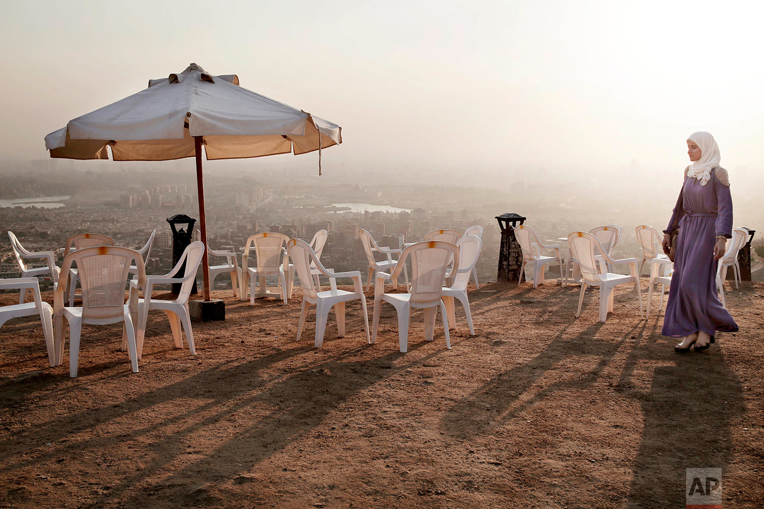  A woman walks on a cliff at sunset in the Moqattam district, overlooking Greater Cairo, Egypt, Tuesday, Aug. 22, 2017. Egyptians and a few tourists visit the hills in southeastern Cairo looking for relief from the hottest of the summer days. (AP Pho