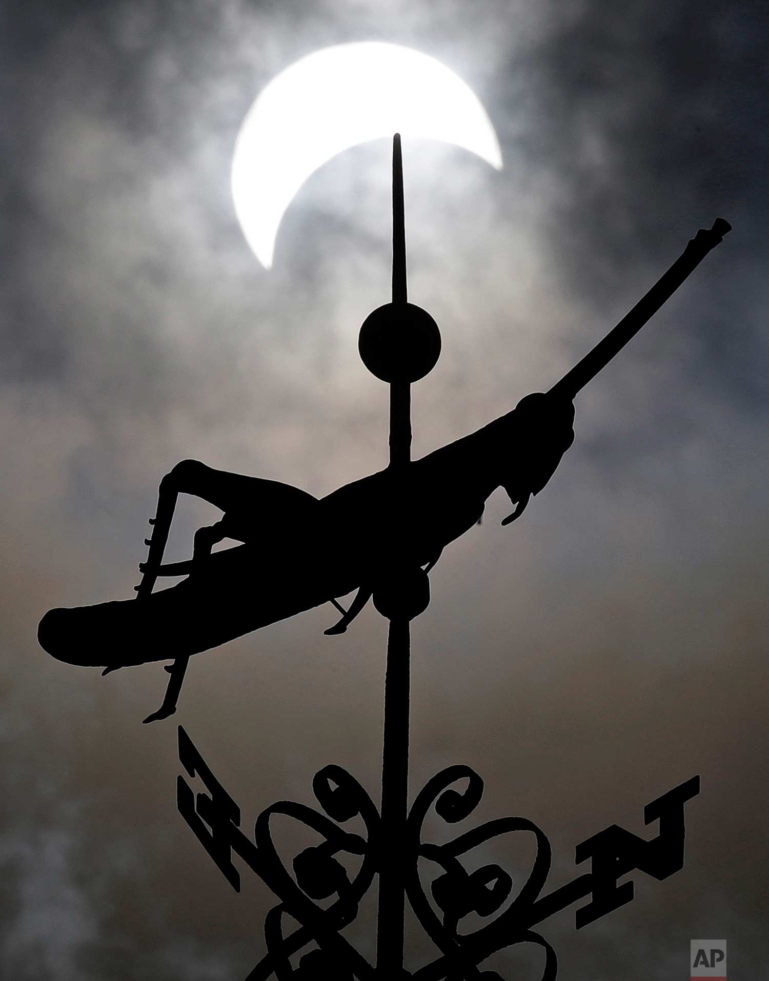  A partial solar eclipse passes over the golden grasshopper weathervane atop historic Faneuil Hall on a cloudy afternoon in Boston, Monday, Aug. 21, 2017. (AP Photo/Charles Krupa) 