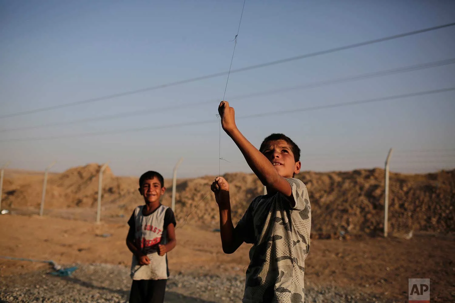 In this Friday, July 21, 2017 photo, seven year-old Omar from Mosul flies a kite in the Chamakor camp for displaced people in northern Iraq. Many displaced can't return to their homes in Iraq's second largest city as their houses are destroyed by air strikes. (AP Photo/Bram Janssen)