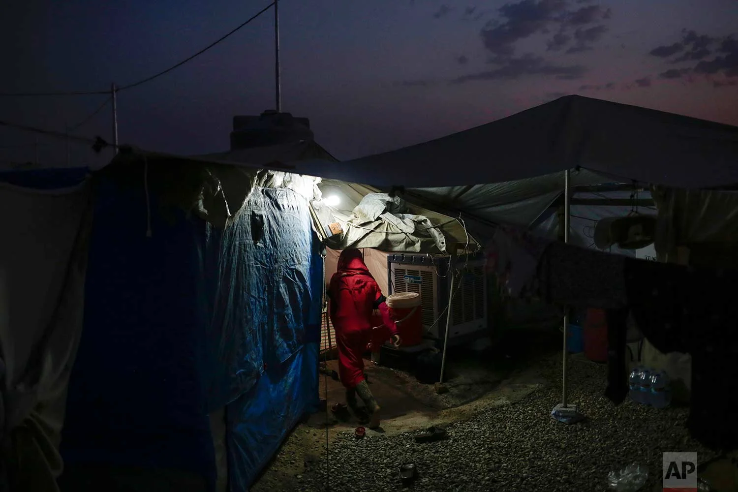 In this Wednesday, Aug. 2, 2017 photo, a girl enters her tent at night in the Hassan Sham camp for displaced people in northern Iraq. (AP Photo/Bram Janssen)