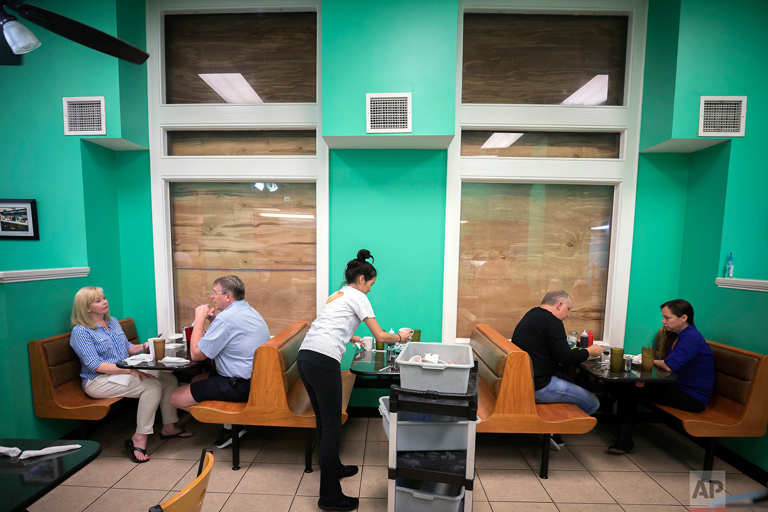  Henry's Restaurant manager Nhi Brayman, center, cleans a table while customers eat breakfast behind boarded up windows, Sunday, Sept., 10, 2017, in downtown Savannah, Ga. (AP Photo/Stephen B. Morton) 