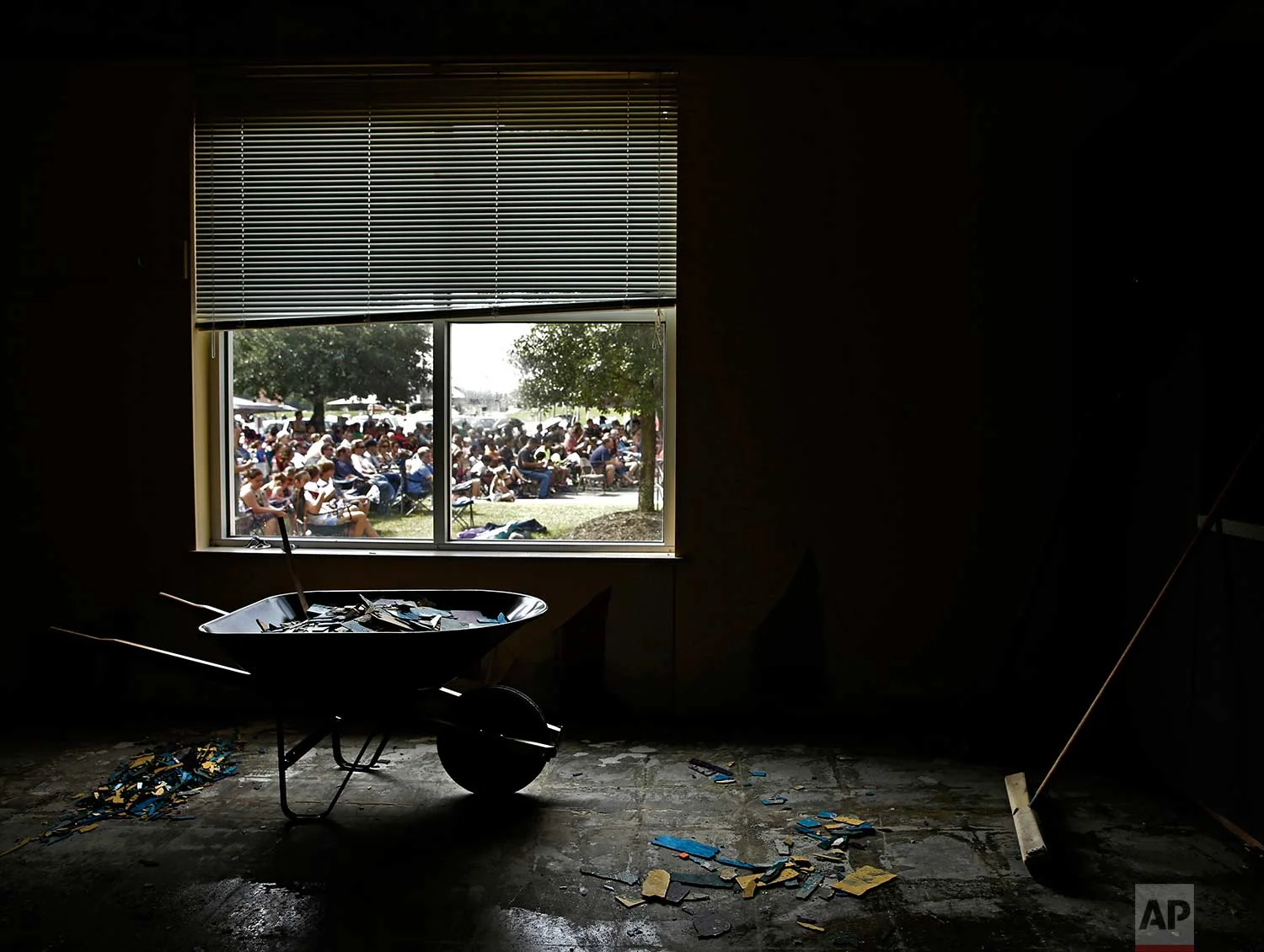 Church members are seen through the window of a water damaged room as they gather in the parking lot of the First Baptist Church for a service Sunday, Sept. 3, 2017, in Humble, Texas. The church building was flooded with two feet of water during Hurricane Harvey, prompting services to be held outside. (AP Photo/Charlie Riedel)