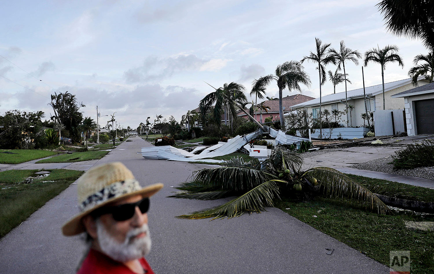  A fallen palm tree and a roof litters a street as Rick Freedman checks his neighborhood's damage from Hurricane Irma in Marco Island, Fla., Monday, Sept. 11, 2017. (AP Photo/David Goldman) 