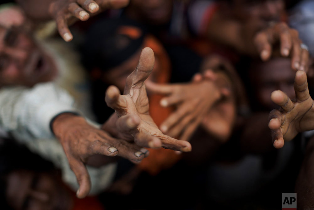  Newly arrived Rohingya stretch out their hands to receive puffed rice food rations donated by local volunteers in Kutupalong, Bangladesh, Saturday, Sept. 9, 2017. (AP Photo/Bernat Armangue) 