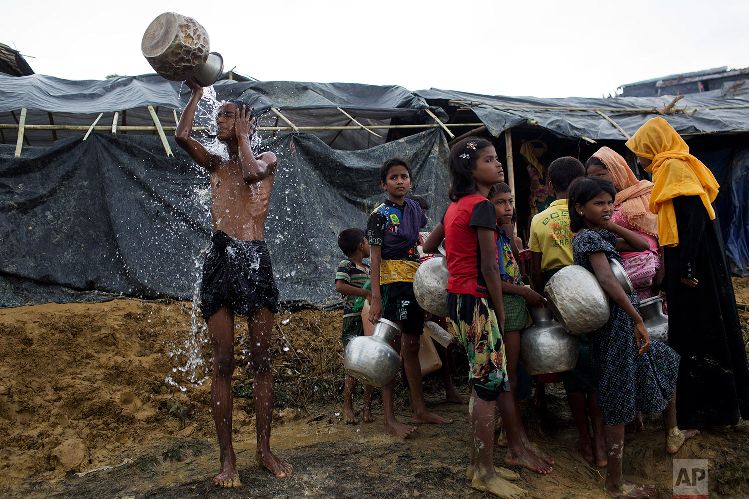  Newly arrived Rohingya wait to collect water from a tube well that was installed a few days ago, as a boy bathes beside them, at Ukhia, Bangladesh, Saturday, Sept. 9, 2017. (AP Photo/Bernat Armangue) 