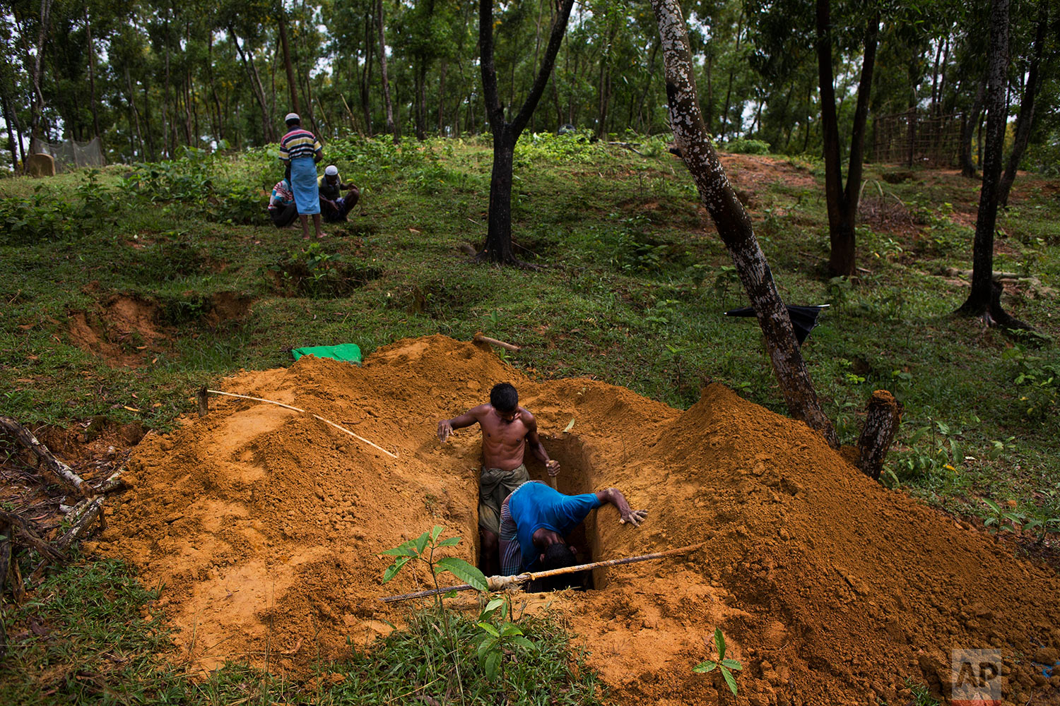  Rohingya men dig a grave in Kutupalong's refugee camp's cemetery, Bangladesh, Friday, Sept. 8, 2017. (AP Photo/Bernat Armangue) 