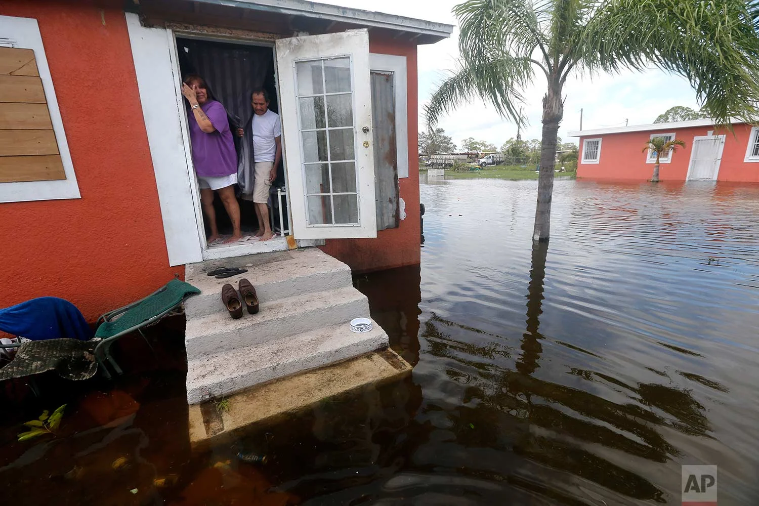 In this Sept. 11, 2017 file photo, Quintana and Liz Perez look at the flooding outside their home in the aftermath of Hurricane Irma, in Immokalee, Fla, one of the poorest towns in the state. Home of many day laborers and migrant workers, Immokalee sustained heavy damage from Irma that will take months to overcome. (AP Photo/Gerald Herbert)