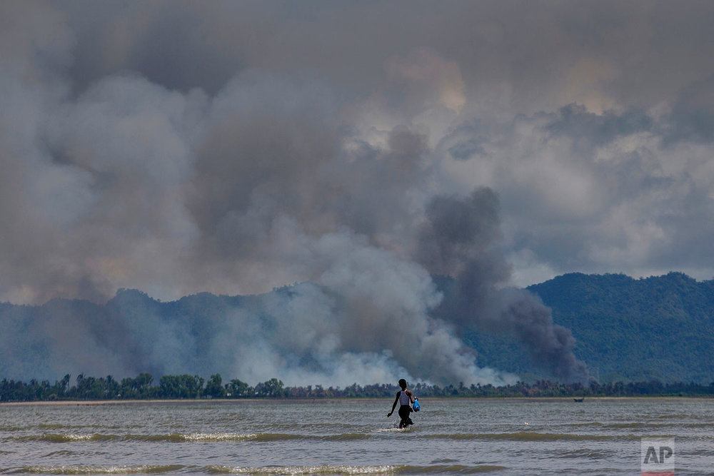  A Bangladeshi boy walks towards a parked boat as smoke rises from across the border in Myanmar, at Shah Porir Dwip, Bangladesh, Thursday, Sept. 14, 2017. Nearly three weeks into a mass exodus of (AP Photo/Dar Yasin) 