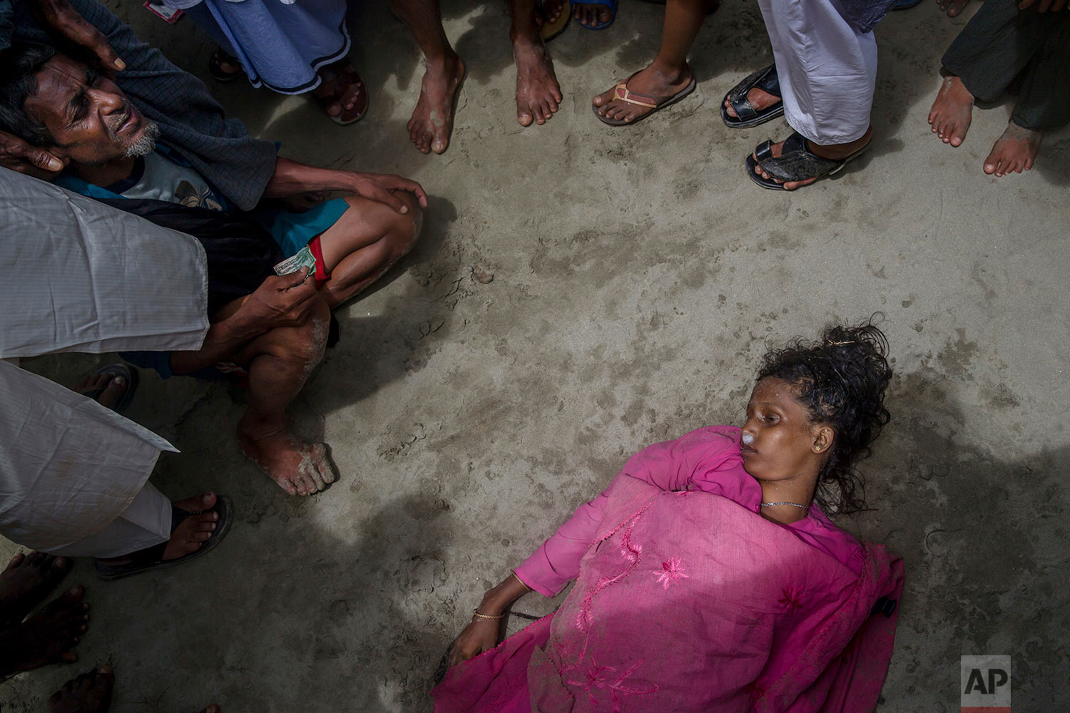  A Rohingya Muslim man Mohammad Islam sits beside the body of his daughter-in-law Anwara Begum who died when the boat they were traveling in capsized minutes before reaching shore in Shah Porir Dwip, Bangladesh, Thursday, Sept. 14, 2017. (AP Photo/Da
