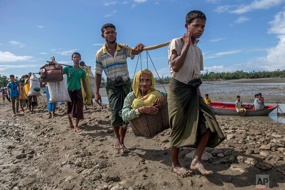  Rohingya Muslims, who crossed over from Myanmar into Bangladesh, carry an elderly woman in a basket and walk towards a refugee camp in Shah Porir Dwip, Bangladesh, Thursday, Sept. 14, 2017. Nearly three weeks into a mass exodus of  (AP Photo/Dar Yas
