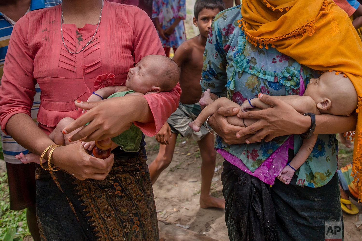  A Rohingya Muslim woman Hanida Begum, right, who crossed over from Myanmar into Bangladesh, holds her infant son Abdul Masood who died when the boat they were traveling in capsized minutes before reaching shore, as a relative holds Masood's twin bro