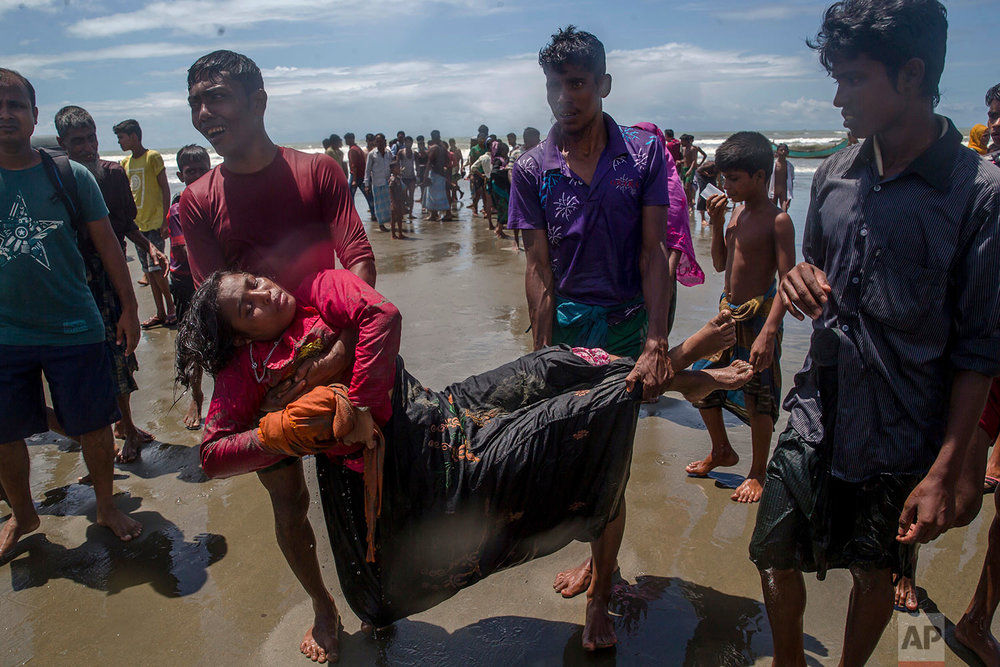  Relatives carry a Rohingya Muslim woman, who fell unconscious when the boat she was traveling in capsized minutes before reaching shore, towards a medical center for treatment at Shah Porir Dwip, Bangladesh, Thursday, Sept. 14, 2017. The woman survi