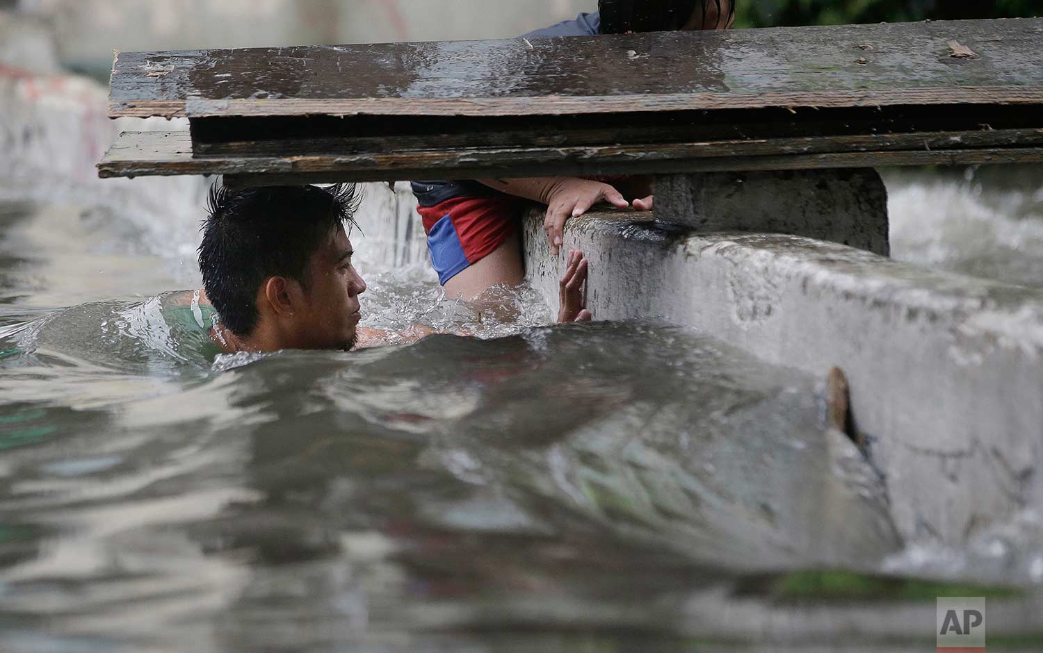 A man swims in a swollen creek as floodwaters continue to rise due to Tropical Depression Maring in Manila, Philippines, on Tuesday, Sept. 12, 2017. Classes in schools and work in government offices have been suspended in the capital and nearby provinces as heavy rains create flooding in low-lying areas. (AP Photo/Aaron Favila)