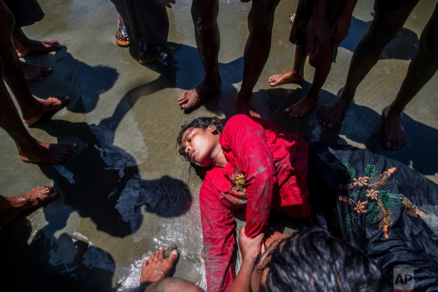 A Rohingya Muslim woman, who crossed over from Myanmar into Bangladesh, lies unconscious on the shore of the Bay of Bangal after the boat she was traveling in capsized at Shah Porir Dwip, Bangladesh, Thursday, Sept. 14, 2017. Nearly three weeks into a mass exodus of Rohingya fleeing violence in Myanmar, thousands were still flooding across the border Thursday in search of help and safety in teeming refugee settlements in Bangladesh. (AP Photo/Dar Yasin)
