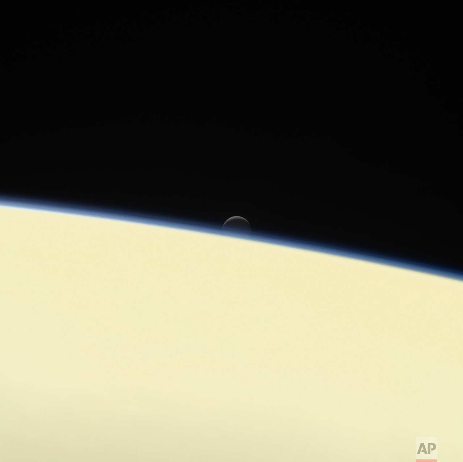  This image made available by NASA shows the moon Enceladus and the edge of Saturn as seen from the Cassini spacecraft on its descent towards the planet on Wednesday, Sept. 13, 2017. The probe disintegrated in the skies above Saturn early Friday, Sep