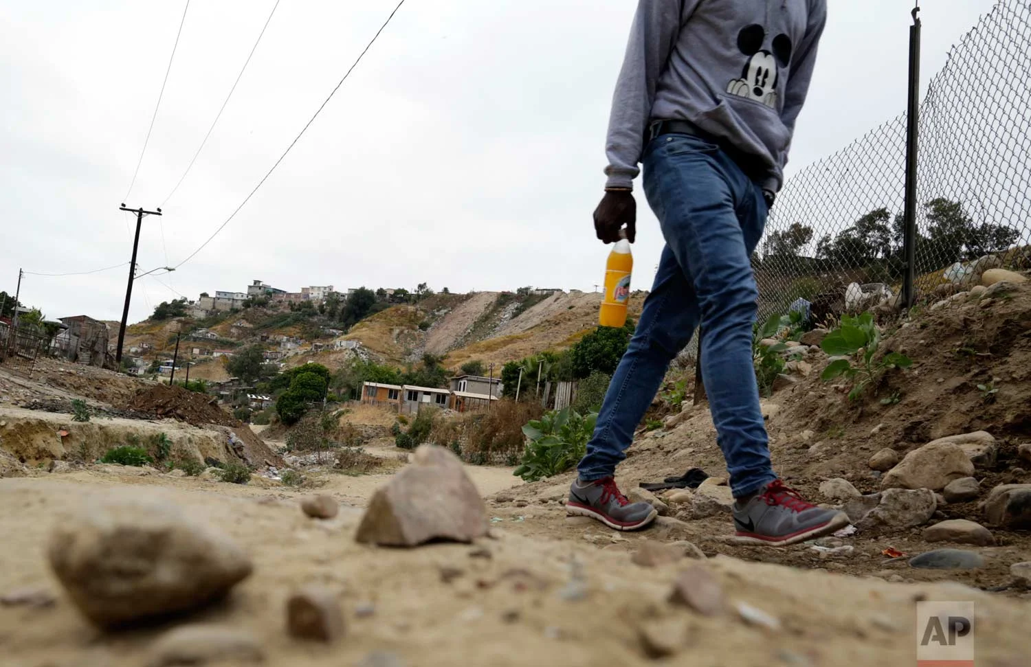 In this May 24, 2017 photo, a Haitian man makes his way up a dirt road towards a makeshift shelter at The Ambassadors of Jesus Church in Tijuana, Mexico. (AP Photo/Gregory Bull)