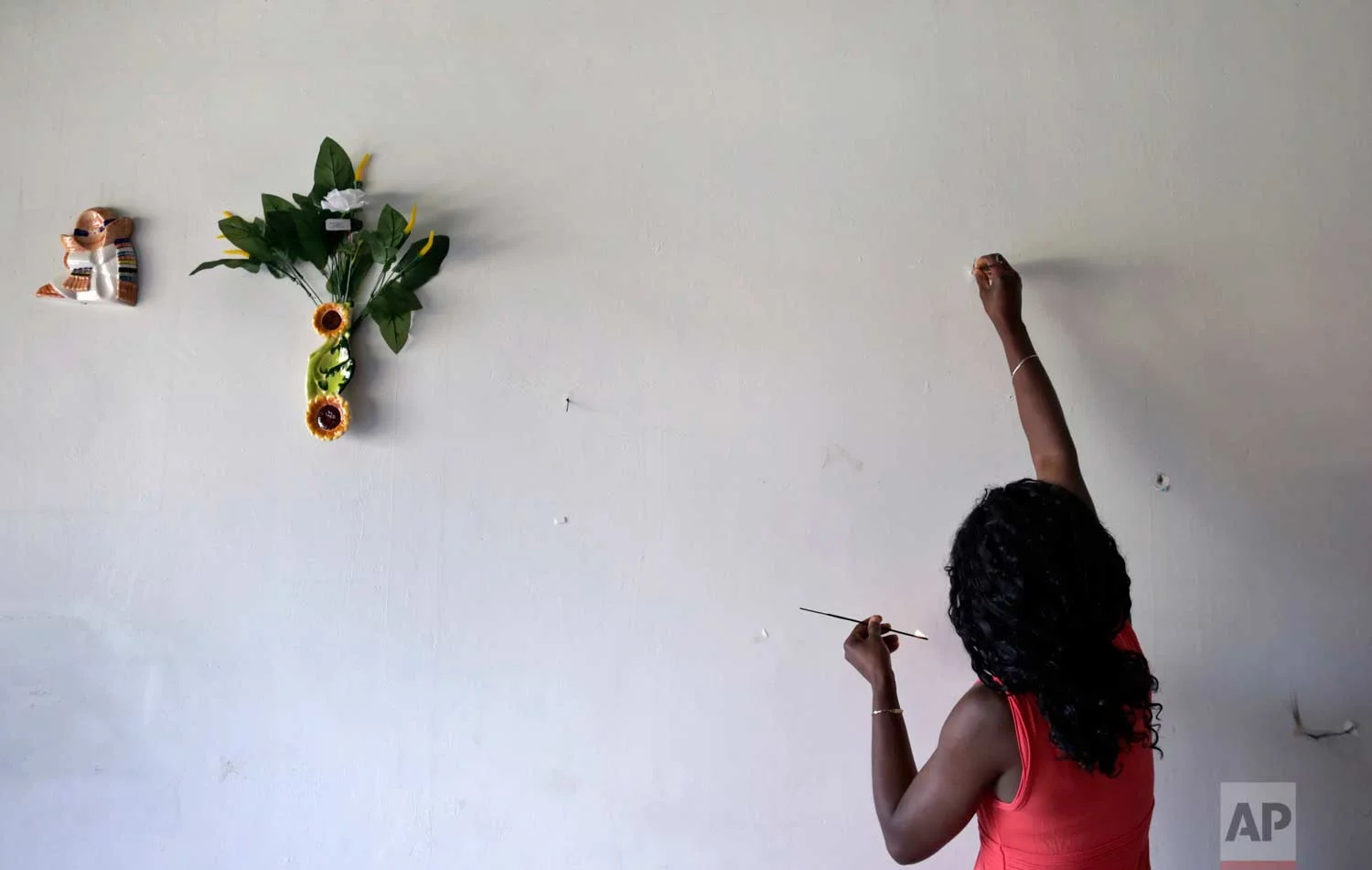 In this May 24, 2017 photo, Lucy Charles, of Haiti, lights incense along a wall in her restaurant specializing in Haitian cuisine in Tijuana, Mexico. (AP Photo/Gregory Bull)