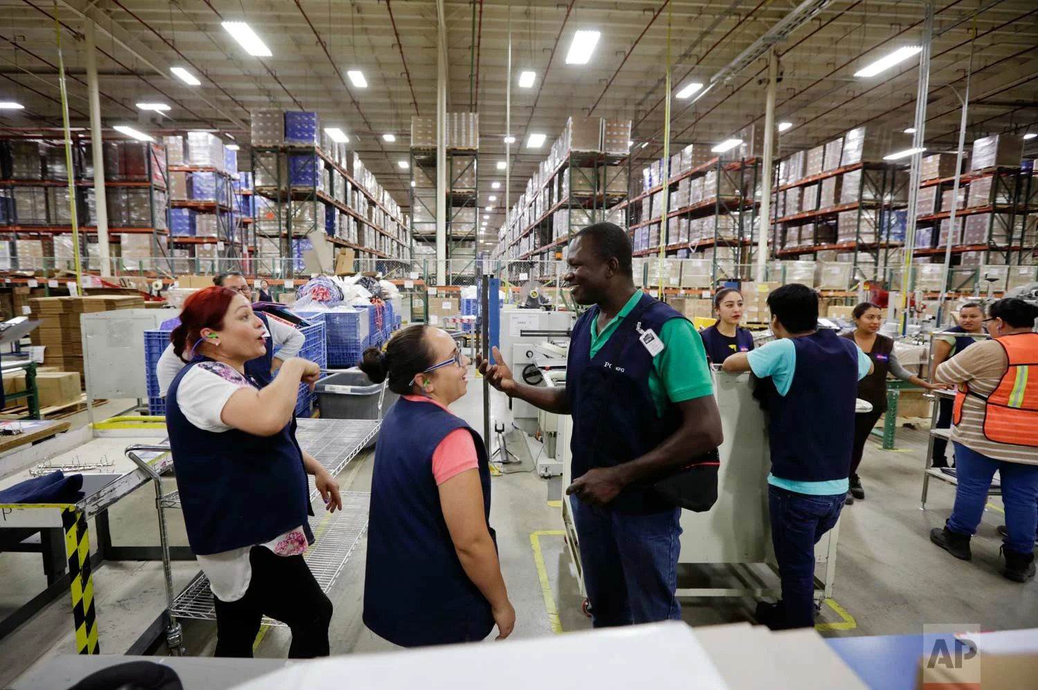 In this June 6, 2017 photo, Evens Presendeaux of Haiti speaks with coworkers on the floor of a factory in Tijuana, Mexico. (AP Photo/Gregory Bull)
